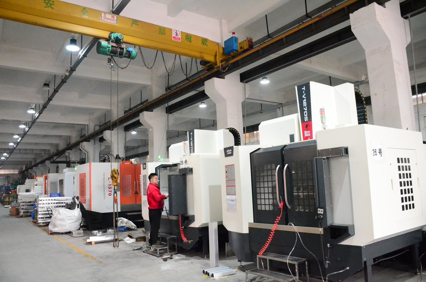 A bay of fifteen CNC machining centres under an overhead crane